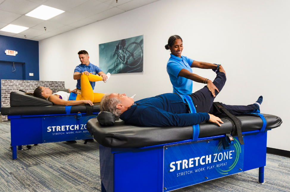 A group of persons being stretched on a massage table