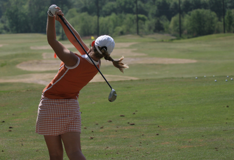 Woman swinging golf